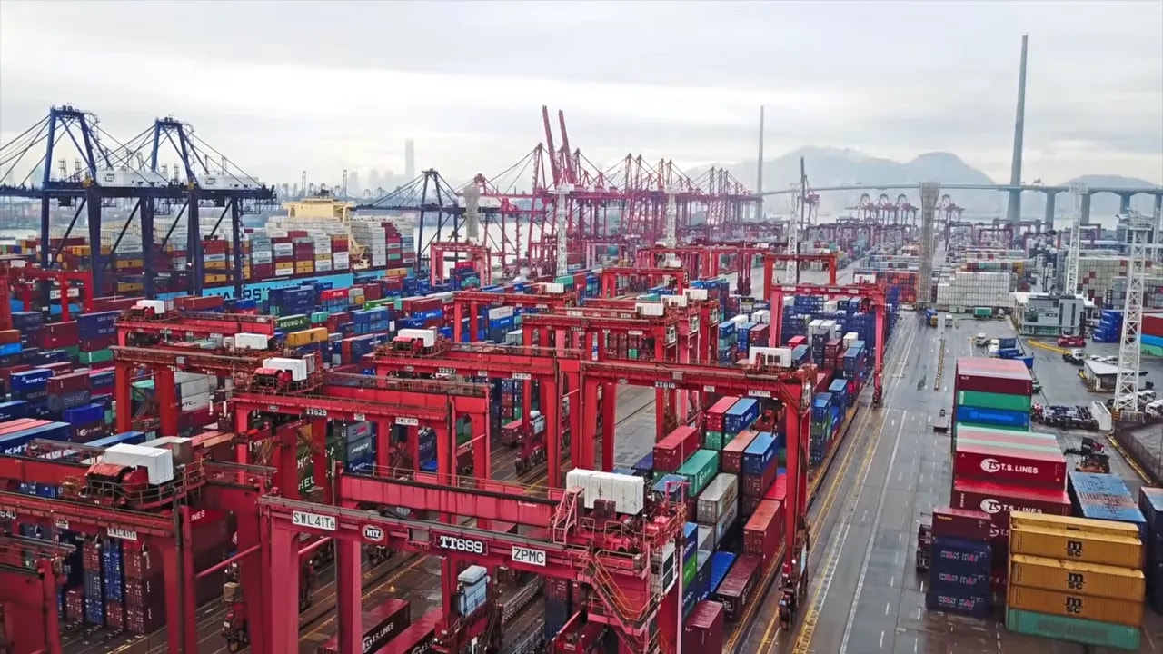 Overhead view of a large container terminal with red cranes and shipping containers