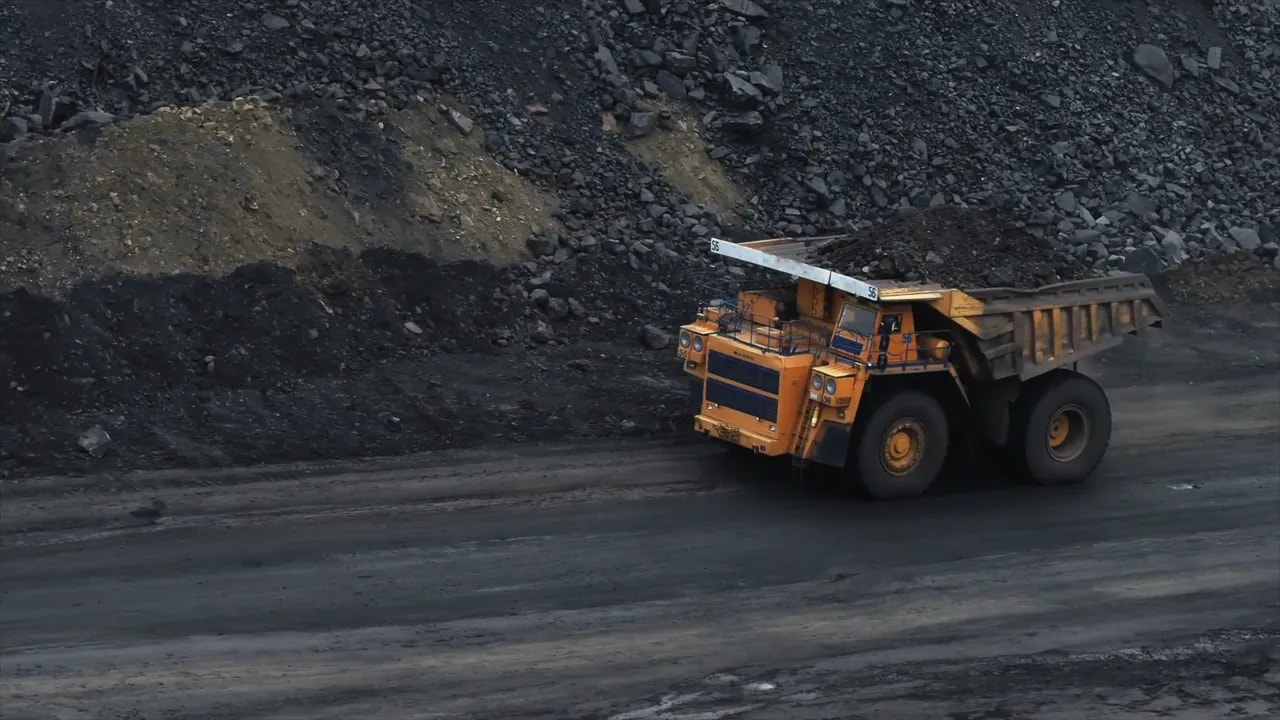 Orange dump truck hauling rock material at an industrial mining and construction site