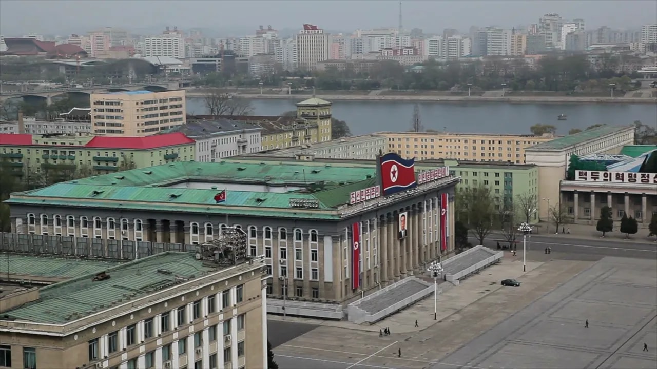 View of Pyongyang government buildings with flags and monument courtyard