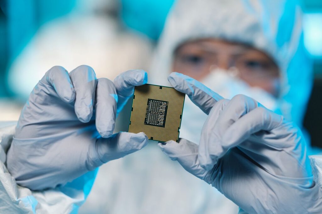 technician holds microchip in cleanroom environment